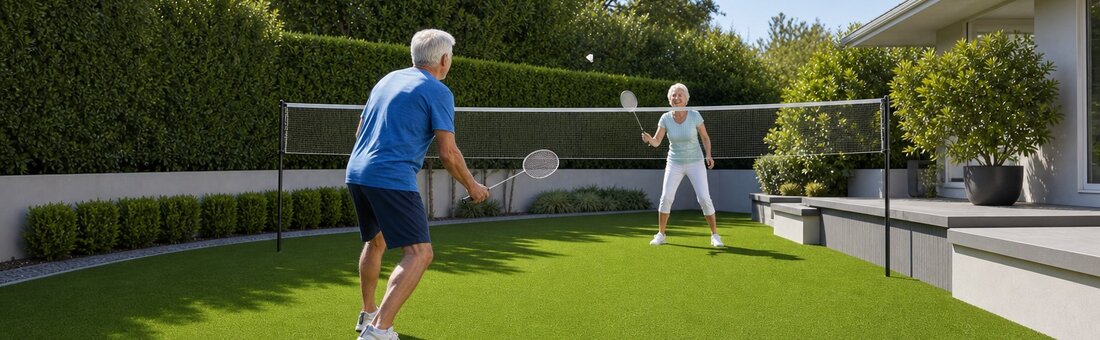 Senior couple playing badminton on a pristine synthetic turf lawn