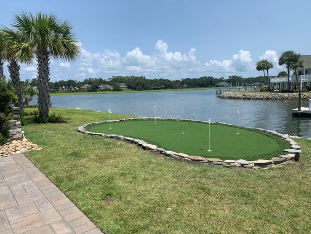Waterfront synthetic turf putting green with a natural stone border overlooking the Intracoastal Waterway in coastal North Carolina
